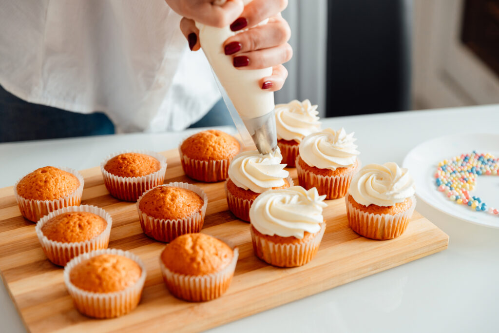 Home baker adding frosting to cupcakes for catering job